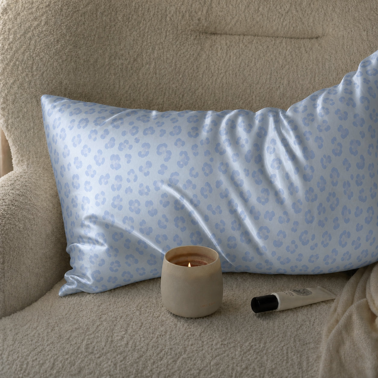 Blue Leopard 22 momme silk front pillowcase styled on a cream lounge chair beside a candle.