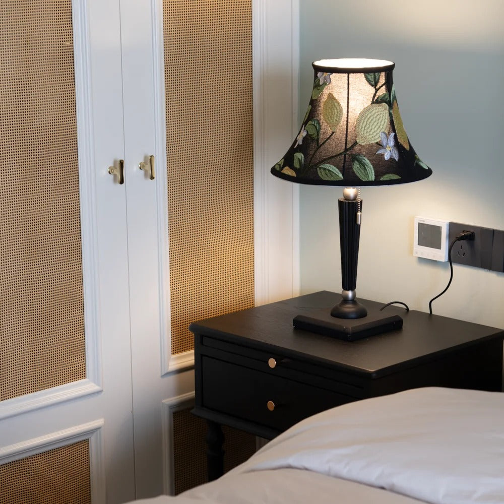 Warm light glowing through lemon-embroidered silk shade in bedroom setting