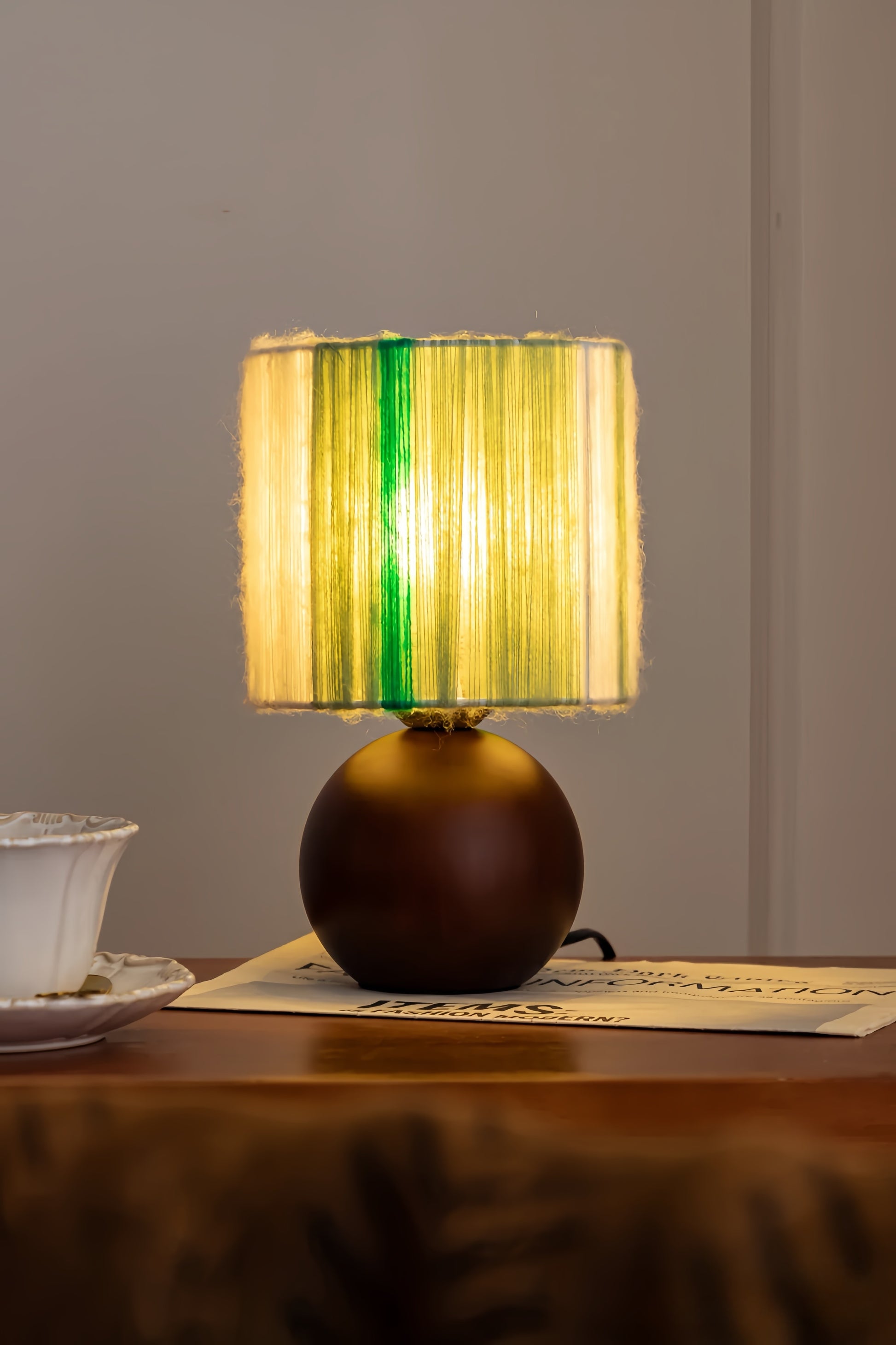 Mohair table lamp with a green and yellow striped shade on a wooden surface.