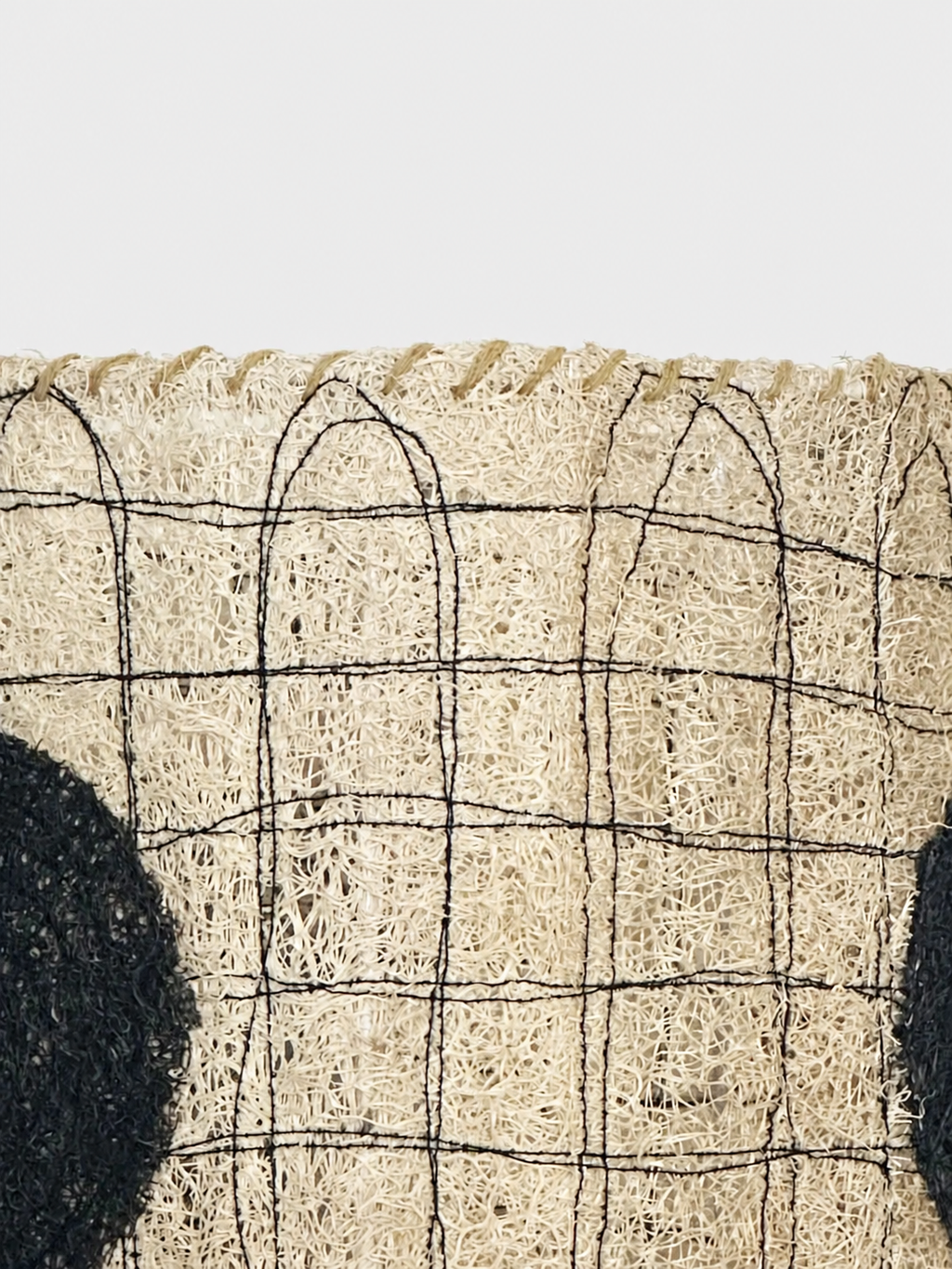 Close-up of the Dottie loofah lampshade showing black stitched grid lines and natural fiber texture