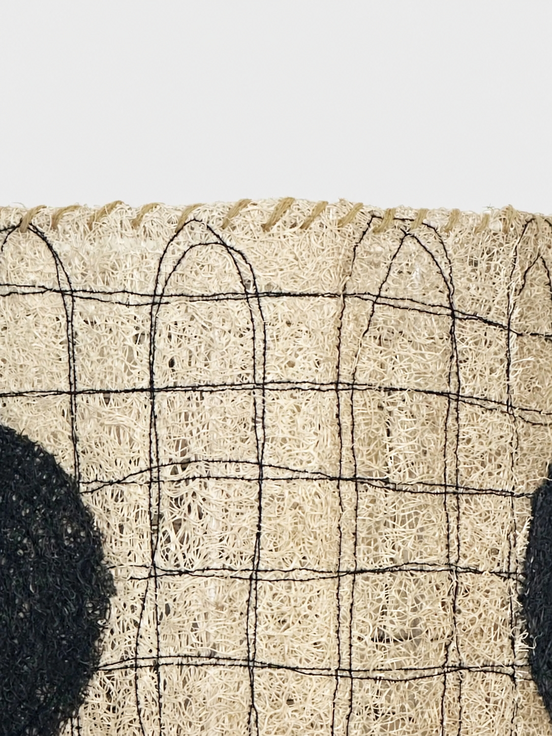 Close-up of the Dottie loofah lampshade showing black stitched grid lines and natural fiber texture