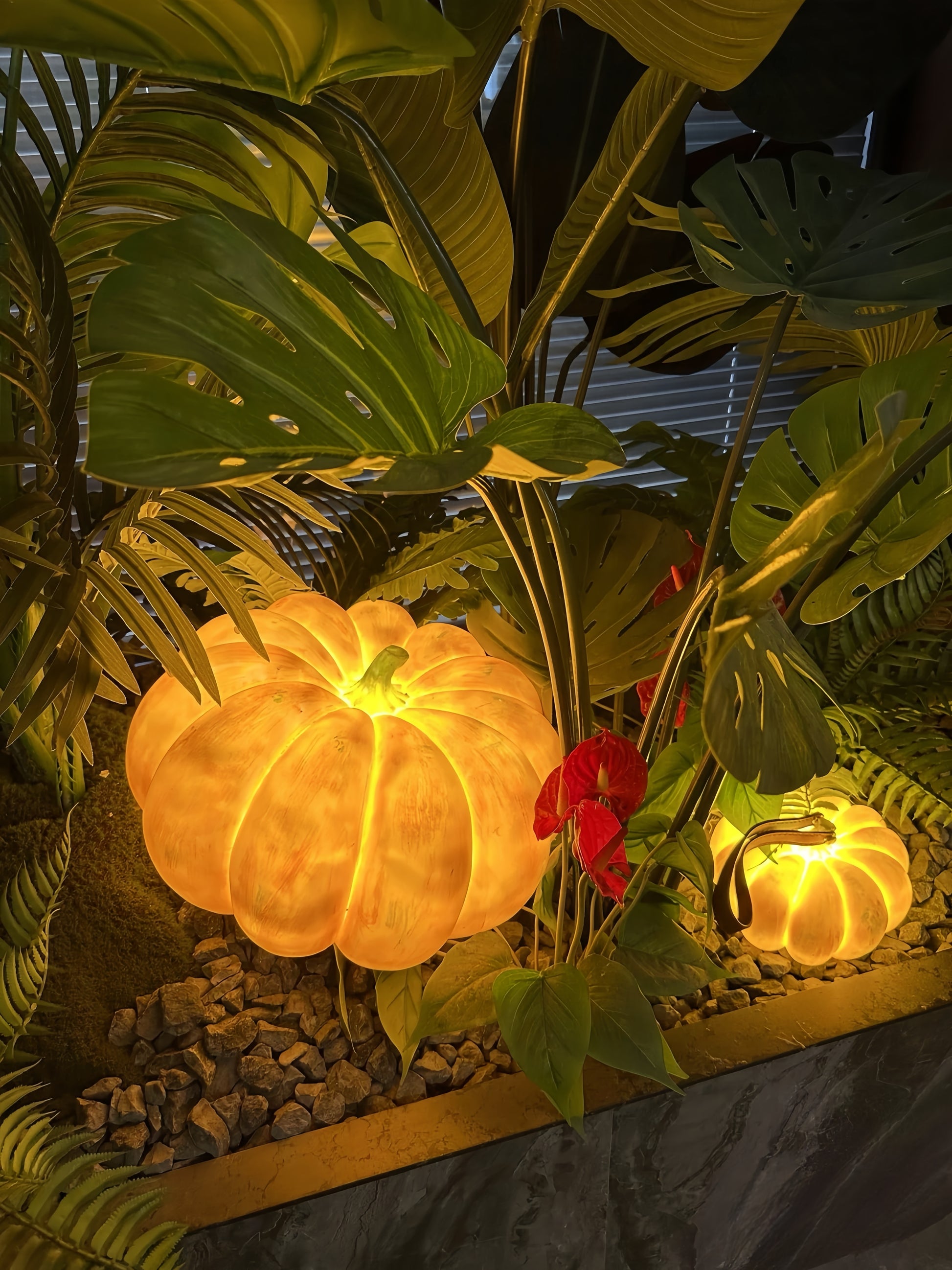Decorative pumpkin lamp with glowing lights surrounded by tropical plants