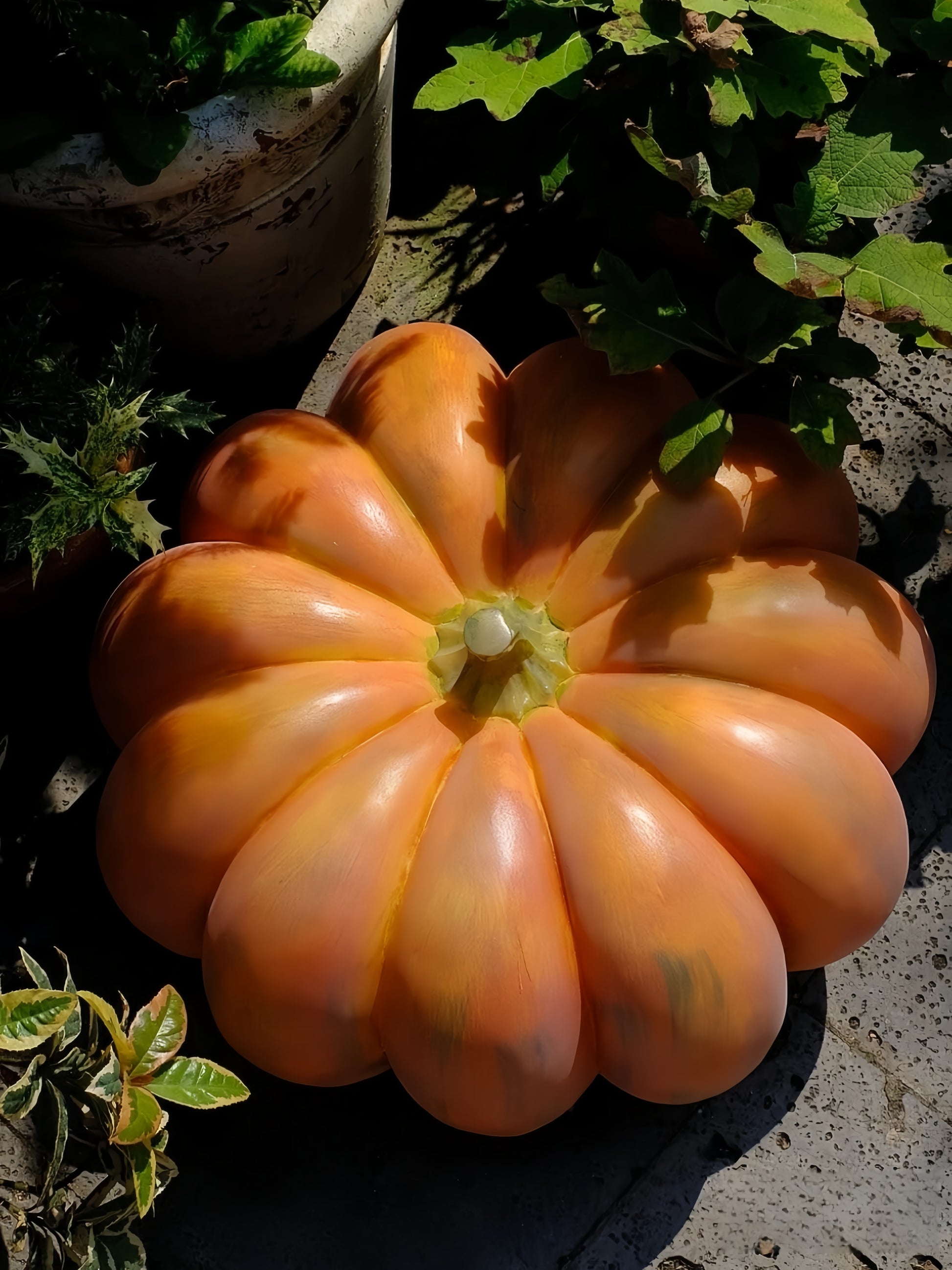 Large orange pumpkin lamp with green leaves on a concrete surface