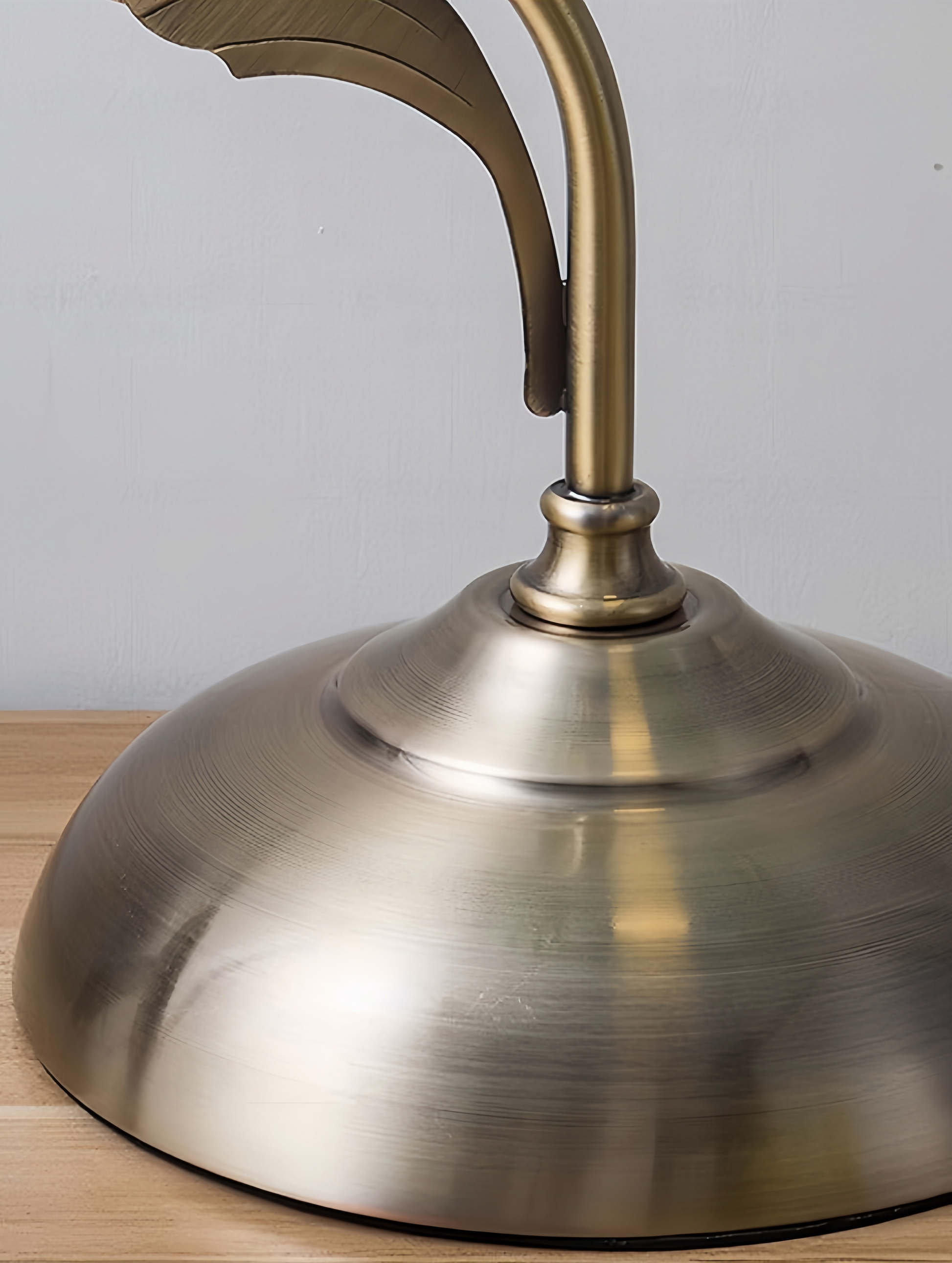 Close-up of a brass MCM lamp base on a wooden surface with a neutral background