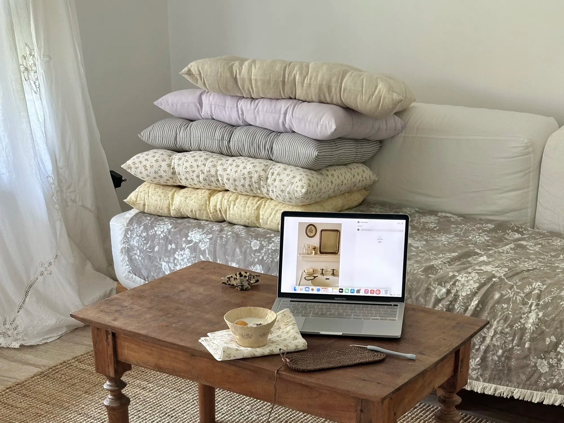 Assorted French vintage patterned pillow cushions styled in a bedroom with a coffee table nearby.