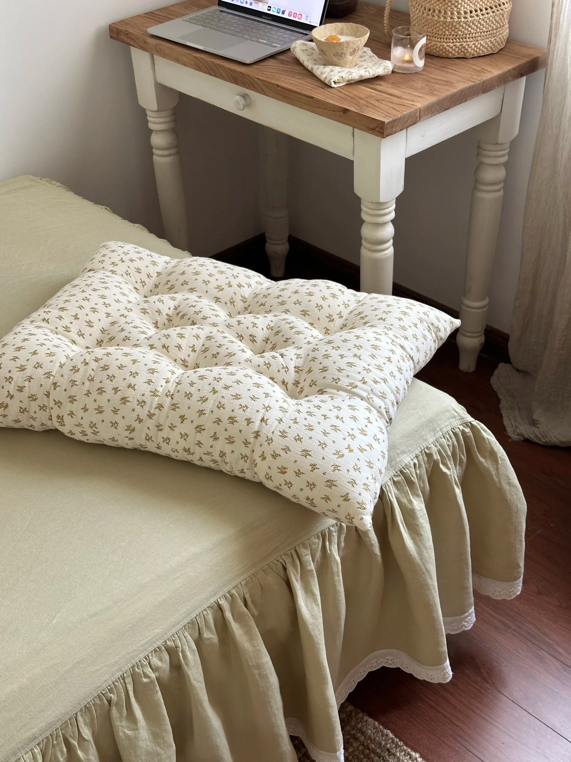 Mustard Floral French vintage patterned pillow cushion styled at the edge of a bed beside a small table.