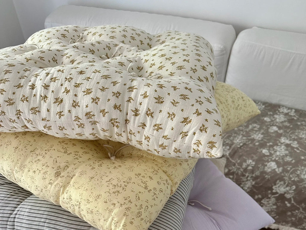 Mustard Floral French vintage patterned pillow cushions stacked with other soft pillows on a bed.