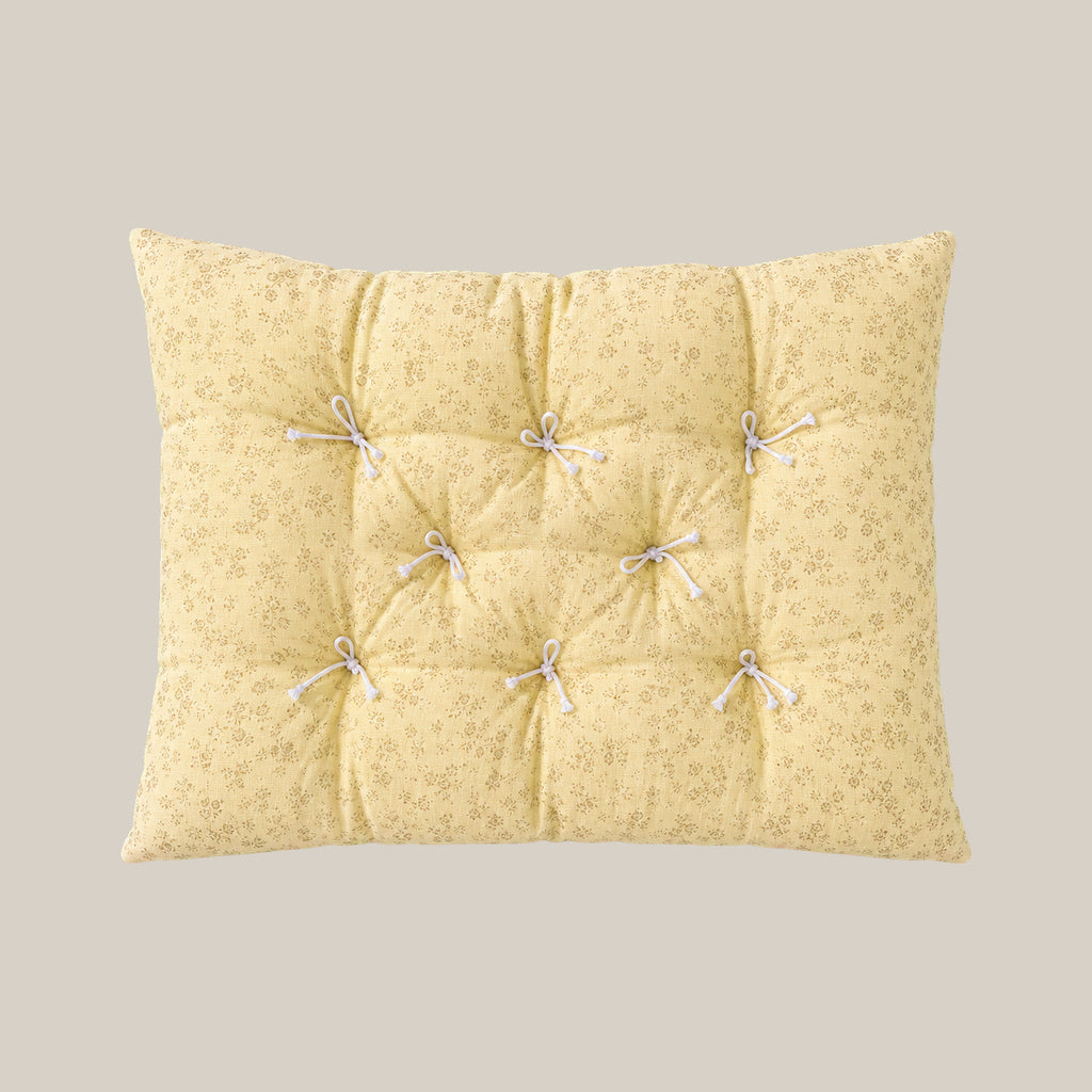 French vintage patterned pillow cushion in Pale Yellow Floral style on a warm beige studio background.