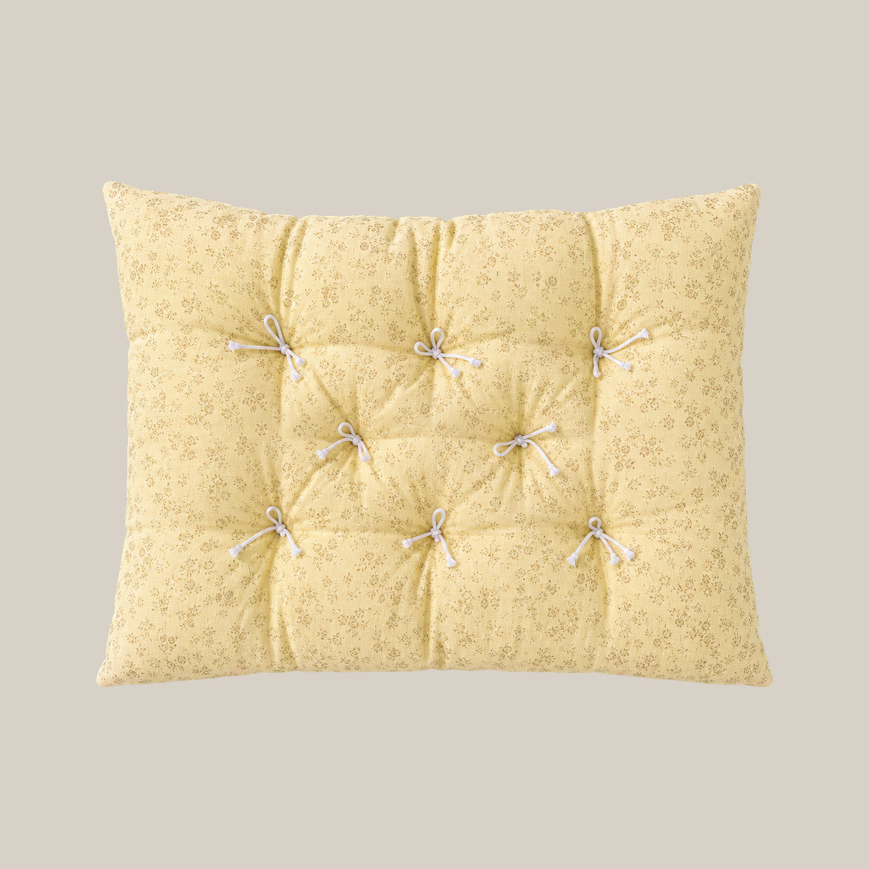 French vintage patterned pillow cushion in Pale Yellow Floral style on a warm beige studio background.