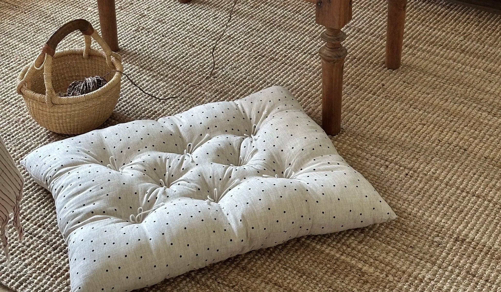Polka Dot French vintage patterned pillow cushion styled on a woven rug near a coffee table.