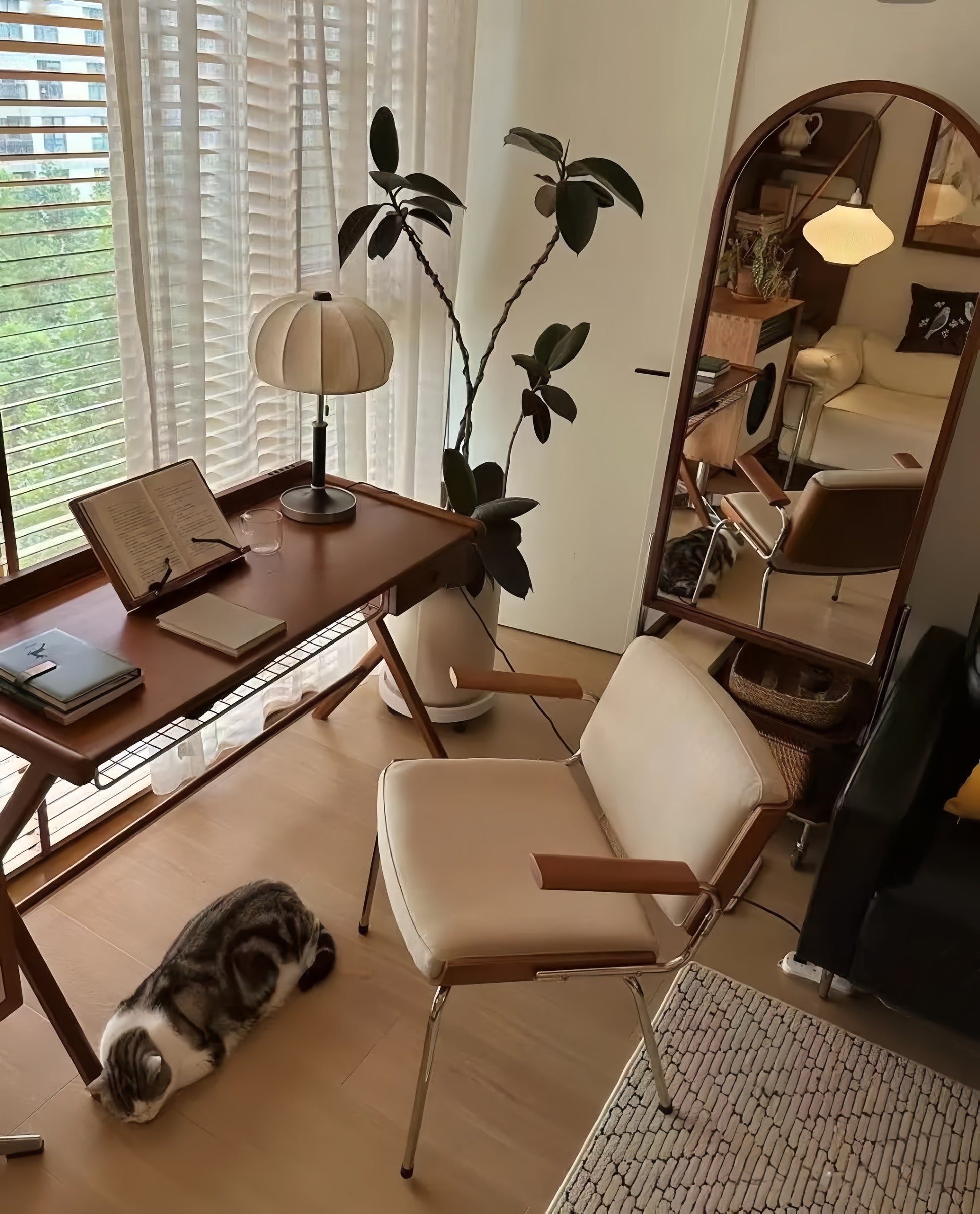 Modern living room with a french vintage desk, chair, and cat near a window.