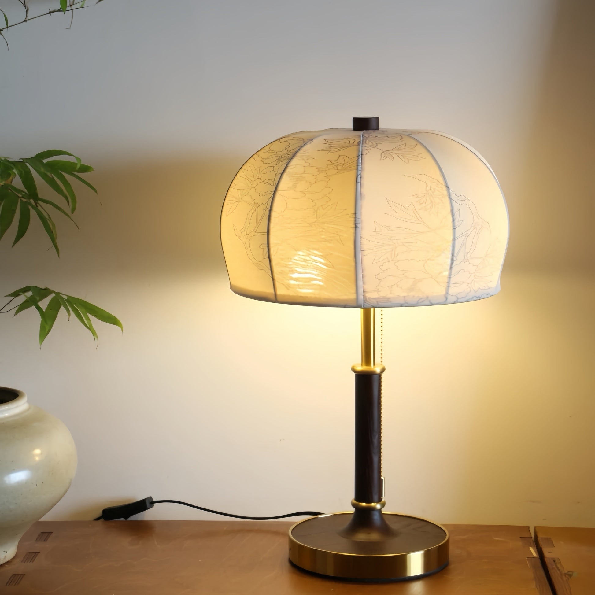 French vintage Table lamp with a textured lampshade on a wooden surface, emitting a warm glow.