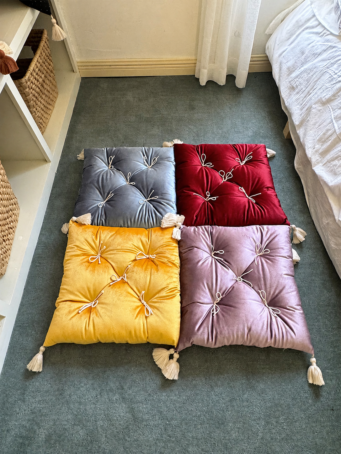 Rouge, yellow, celestial, and purple Léonie velvet tufted tassel throw pillows arranged together.