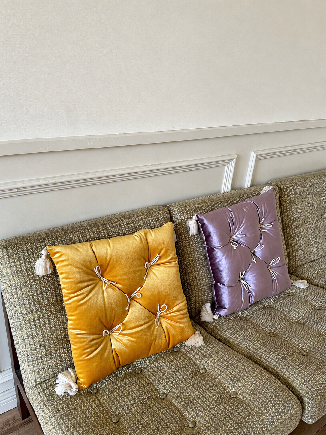 Yellow and Purple Velvet Léonie tufted tassel throw pillows styled on a vintage sofa.