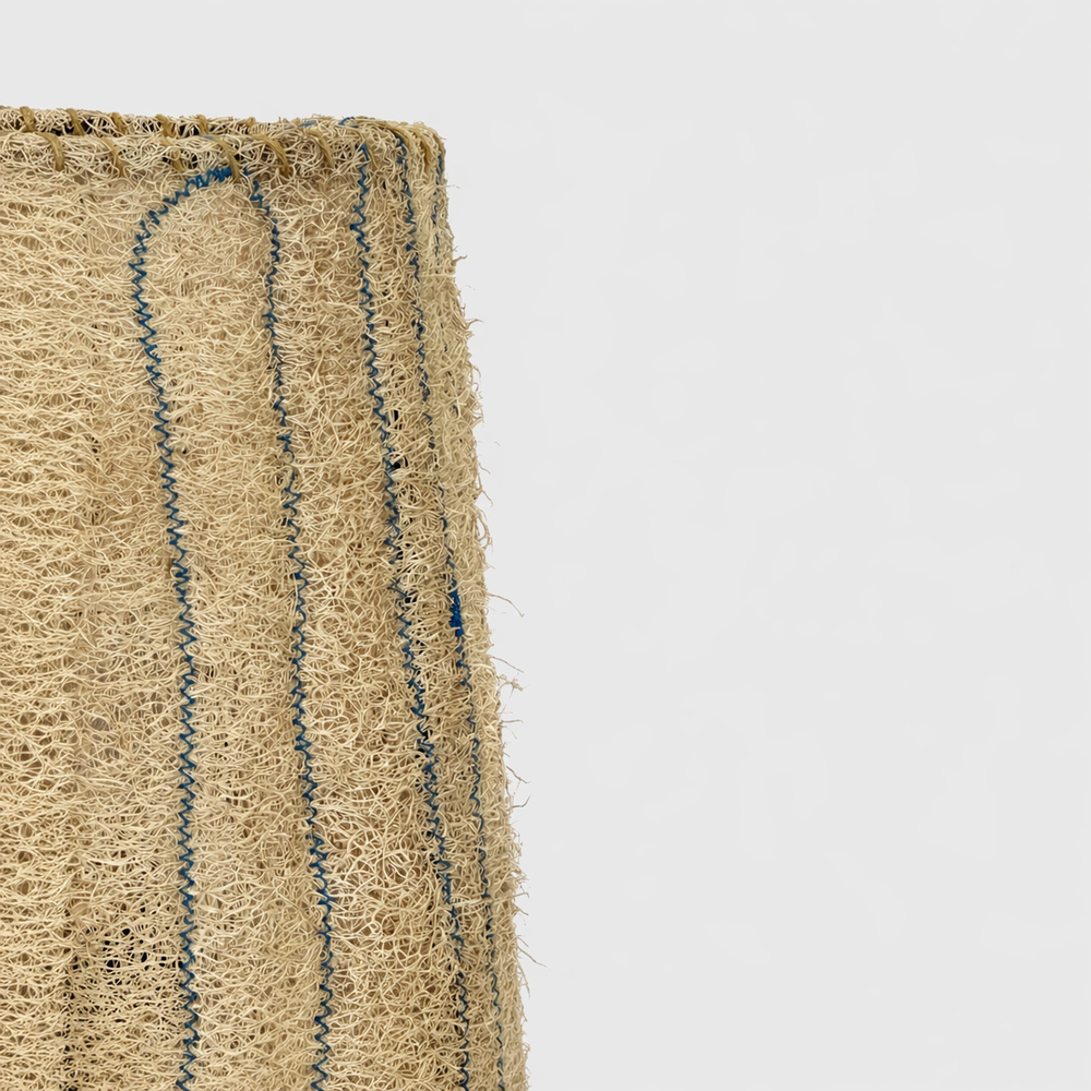 Close-up of the Loop loofah table lamp shade, highlighting handmade stitching and porous natural fiber texture.