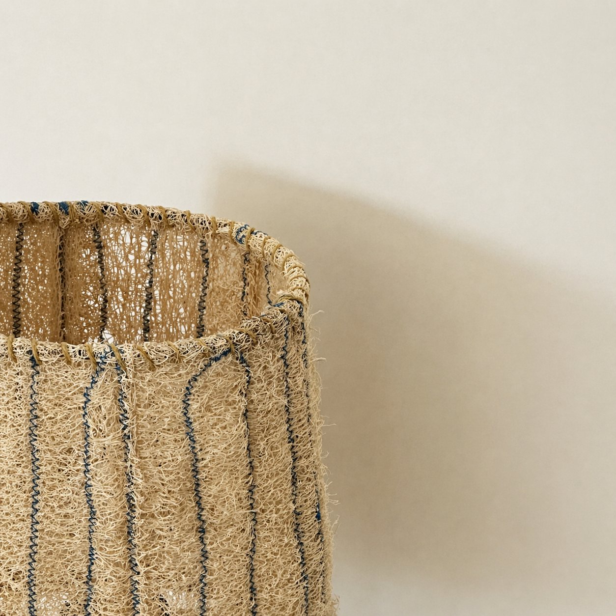 Close-up of the Loop loofah lamp shade top, showing natural woven fiber texture and hand-stitched vertical details.