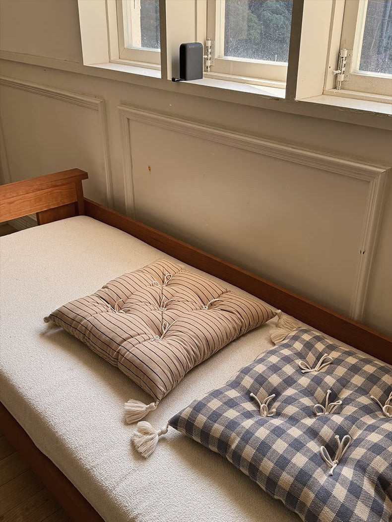 Beige striped and blue plaid Mariette tufted tassel throw pillows on a window bench.