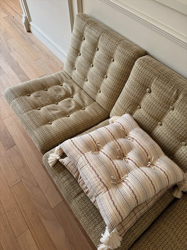 Patterned Mariette tufted tassel throw pillows arranged on a vintage textured sofa.