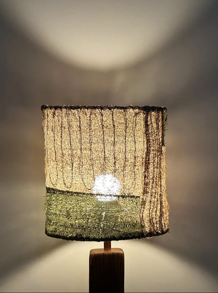 Close-up of the Moss loofah table lamp glowing warmly, highlighting its natural fiber shade texture