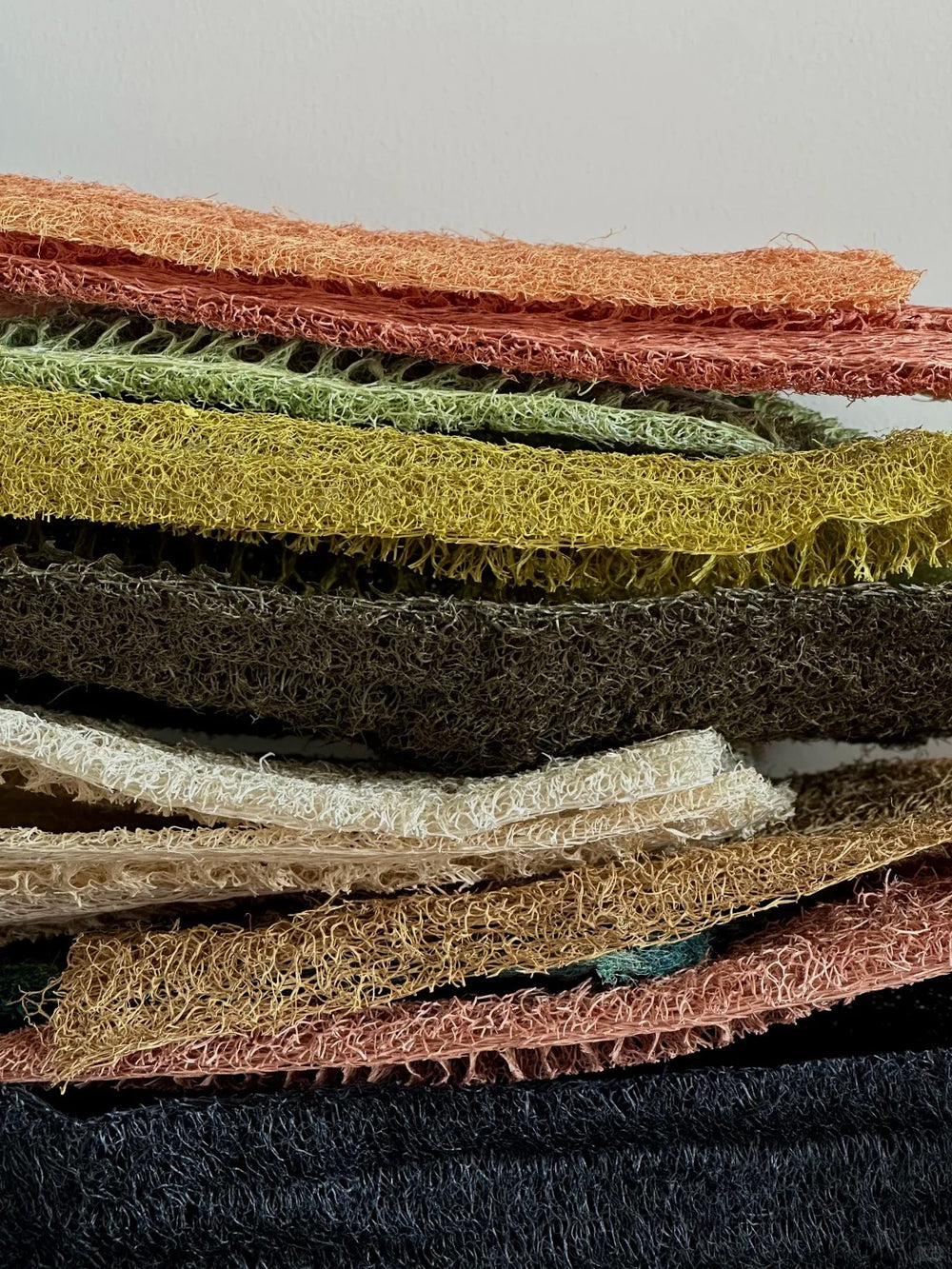 Close-up of stacked dyed loofah fiber sheets showing natural porous texture for handmade lamp shades