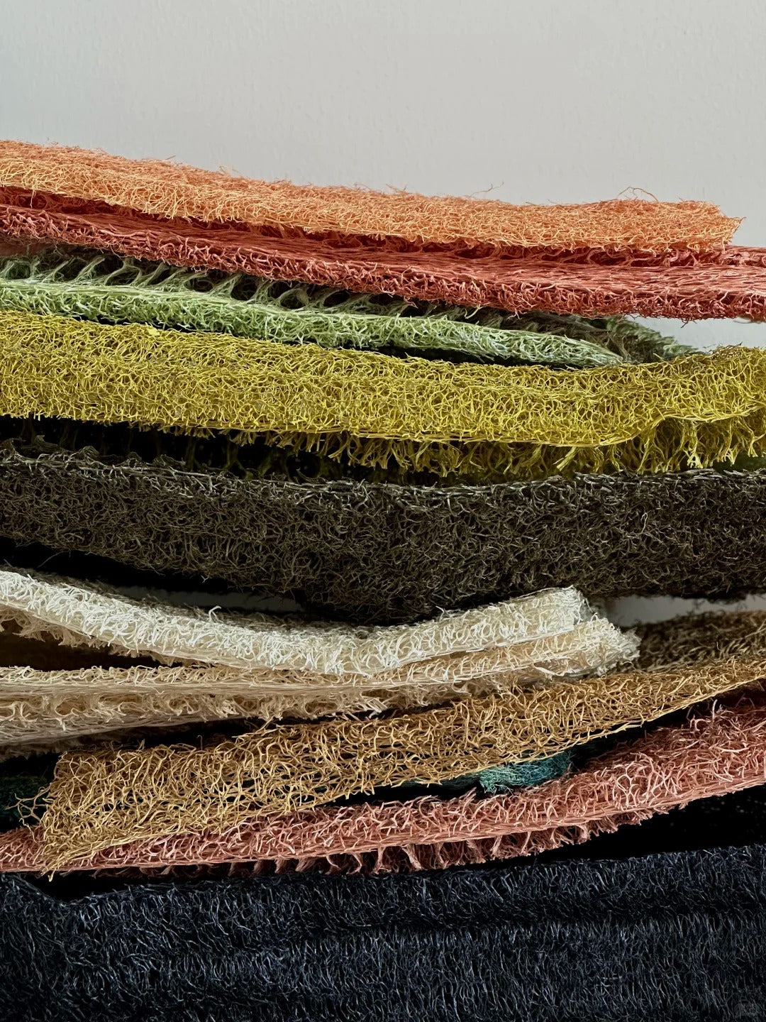Close-up of stacked dyed loofah fiber sheets showing natural porous texture for handmade lamp shades