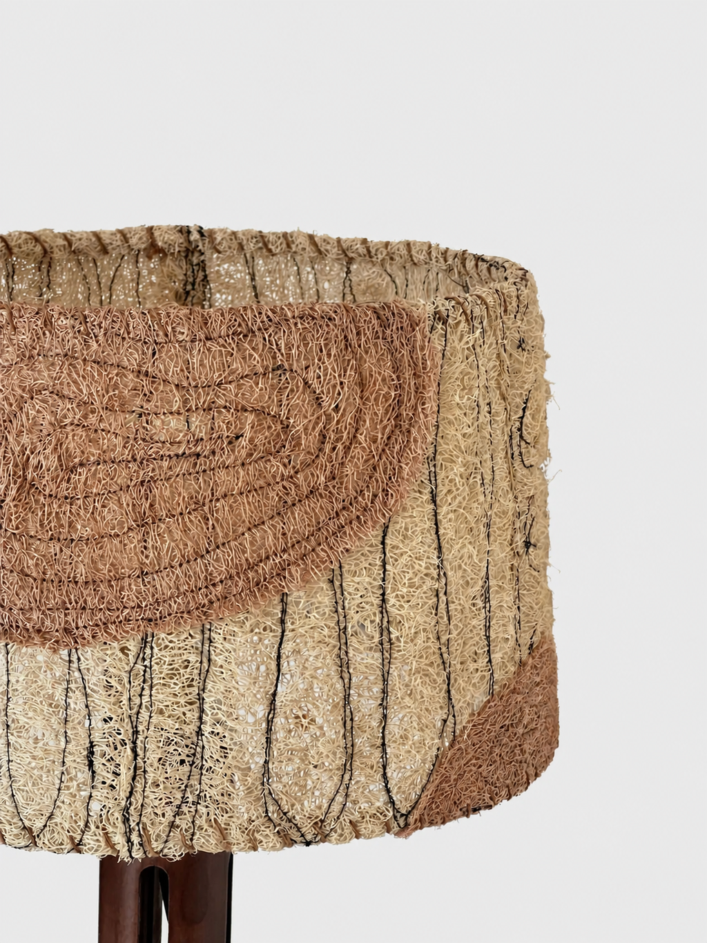 Close-up of the Petal table lamp shade showing natural loofah texture and a blush fiber panel