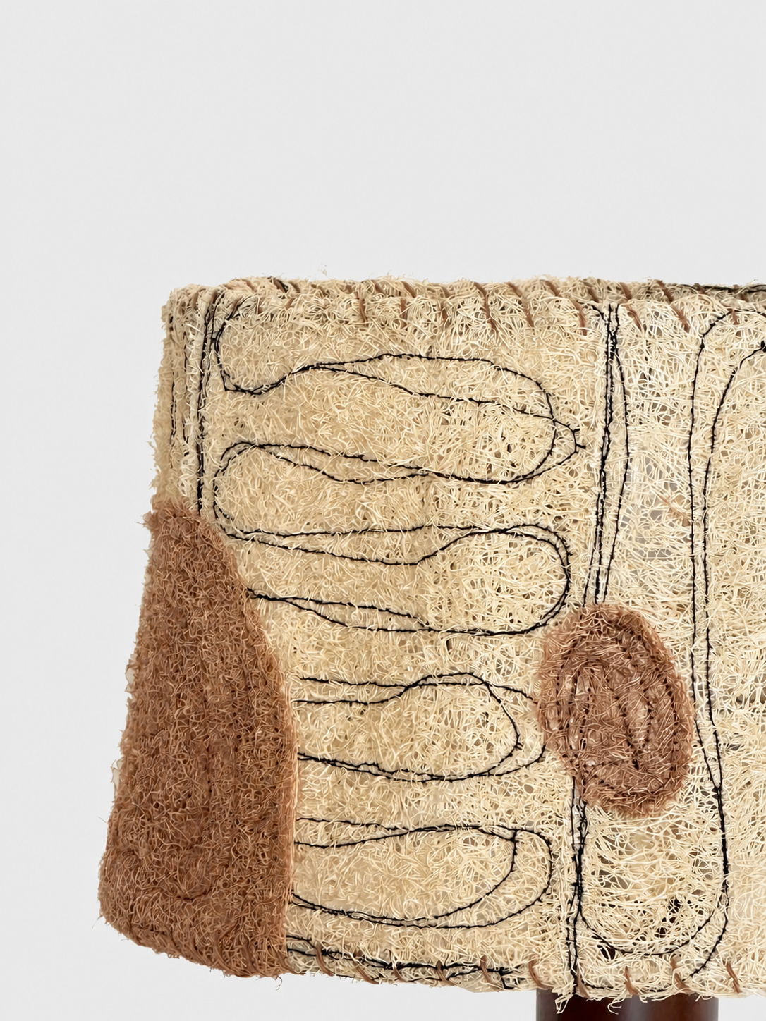Close-up of the Petal loofah lampshade with dark linework and blush fiber accents