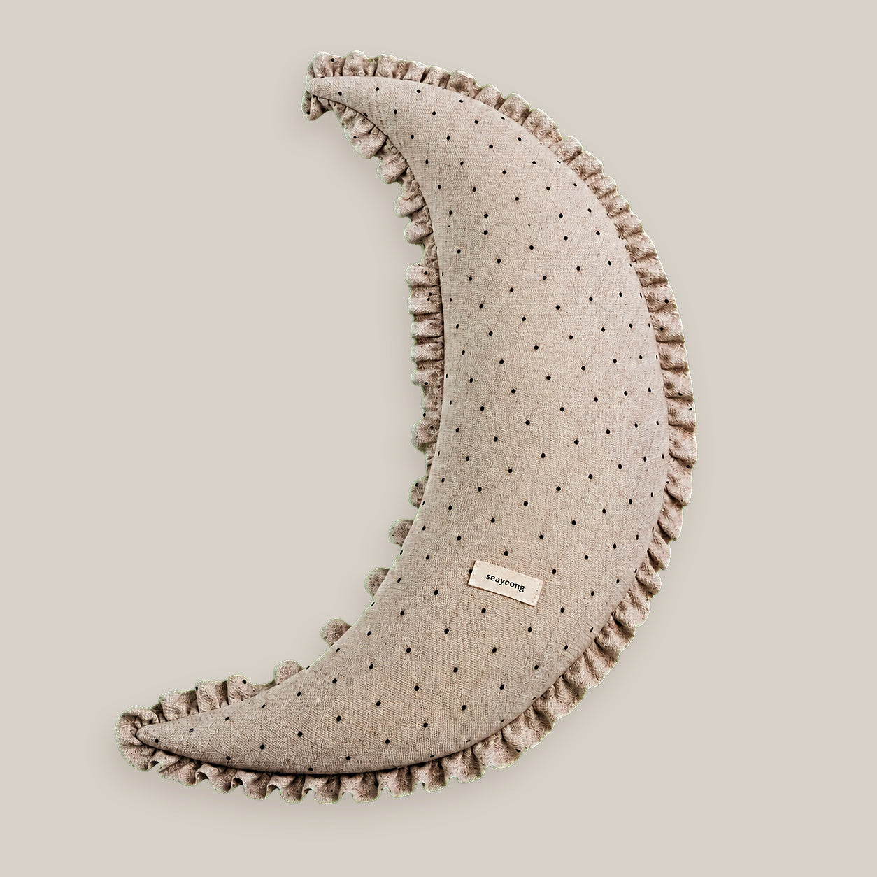 Polka dot linen moon body pillow cushion on a warm beige studio background.