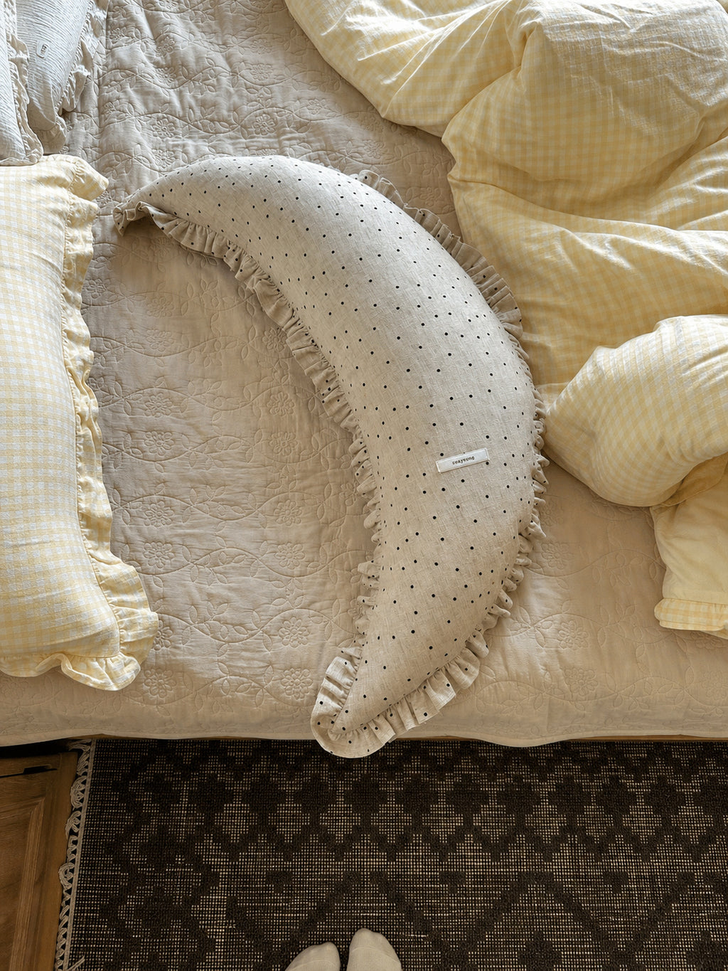 Overhead lifestyle view of the polka dot linen moon body pillow cushion on quilted bedding.