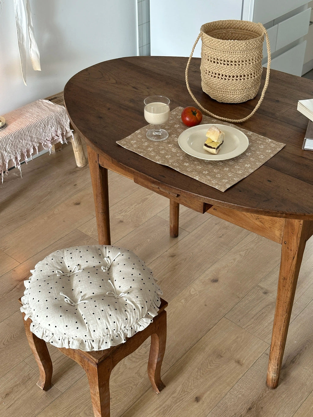 Cream polka dot round chair cushion with bow ties and a ruffled edge in a rustic dining room.