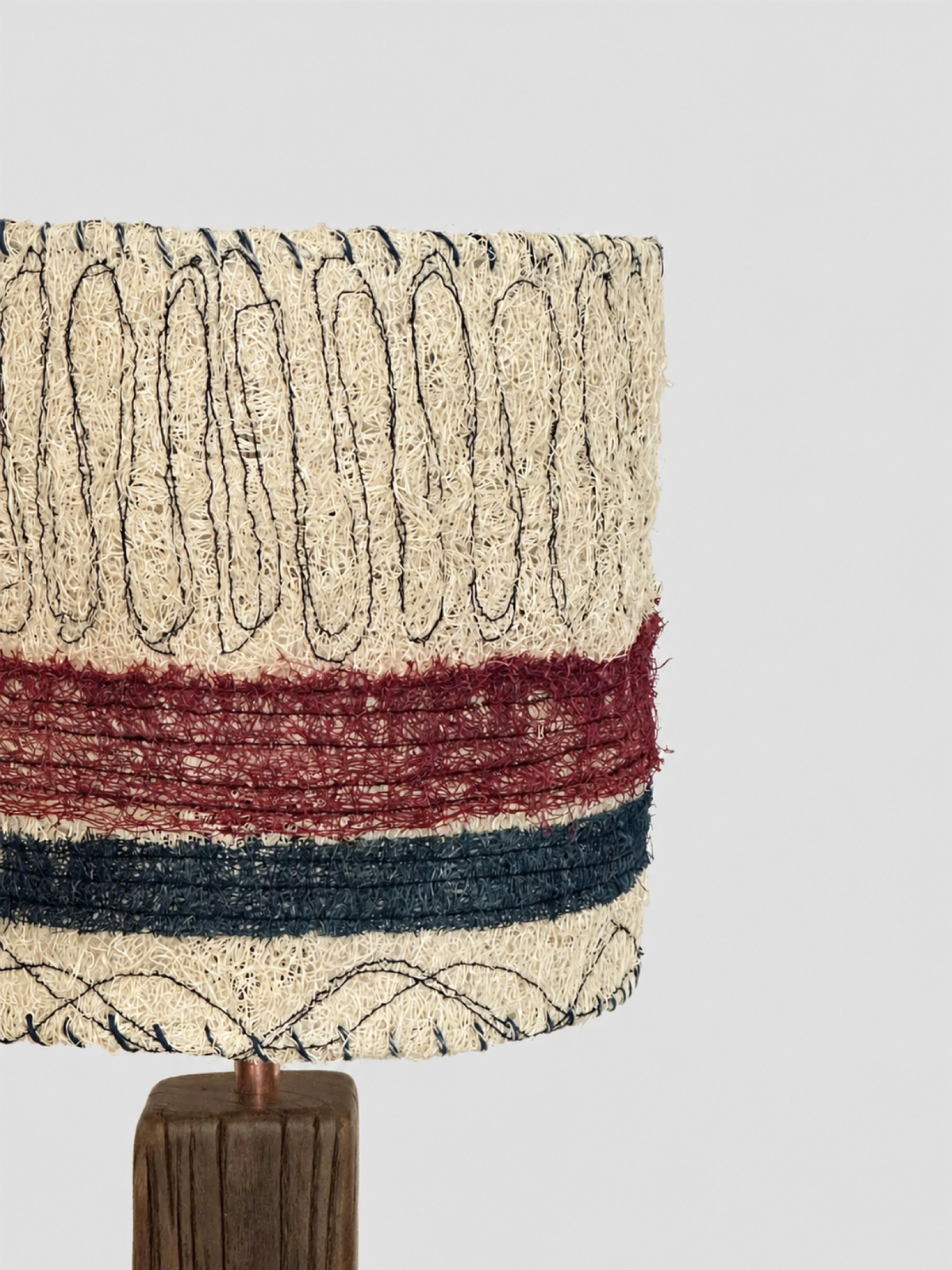 Side detail of the loofah lampshade texture, stitched pattern, and wood stem
