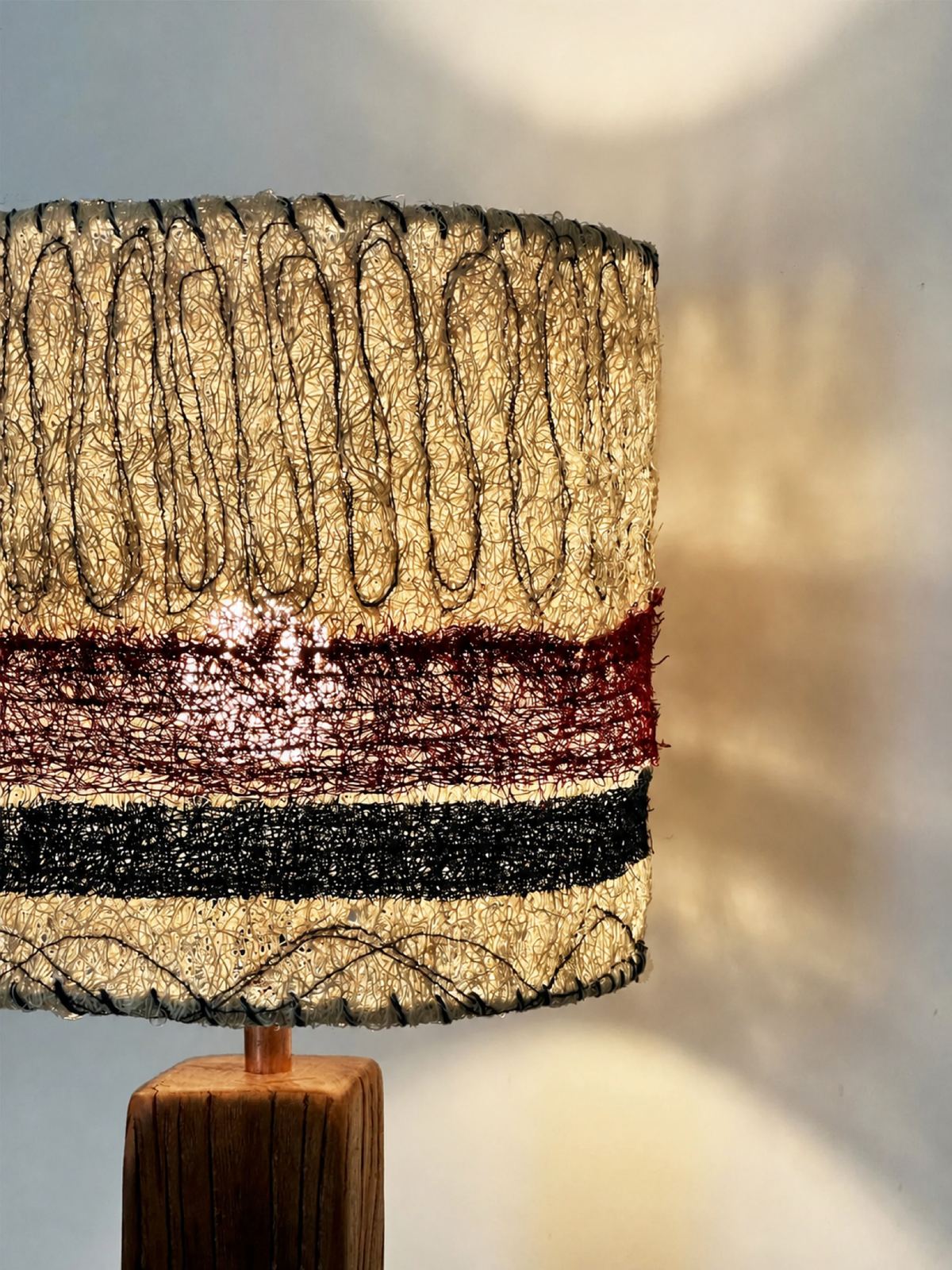 Lit loofah table lamp showing warm light through the woven shade and wall glow
