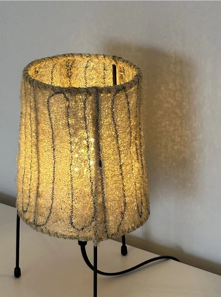 Wabi-Sabi Loofah Fiber Tripod Table Lamp - Loop illuminated and casting a warm amber glow in a dimly lit room