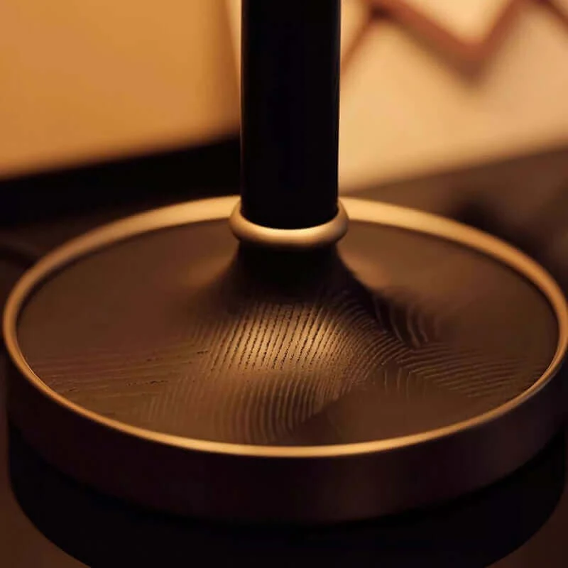 low-angle close-up of the dark circular base with brass trim and stem
