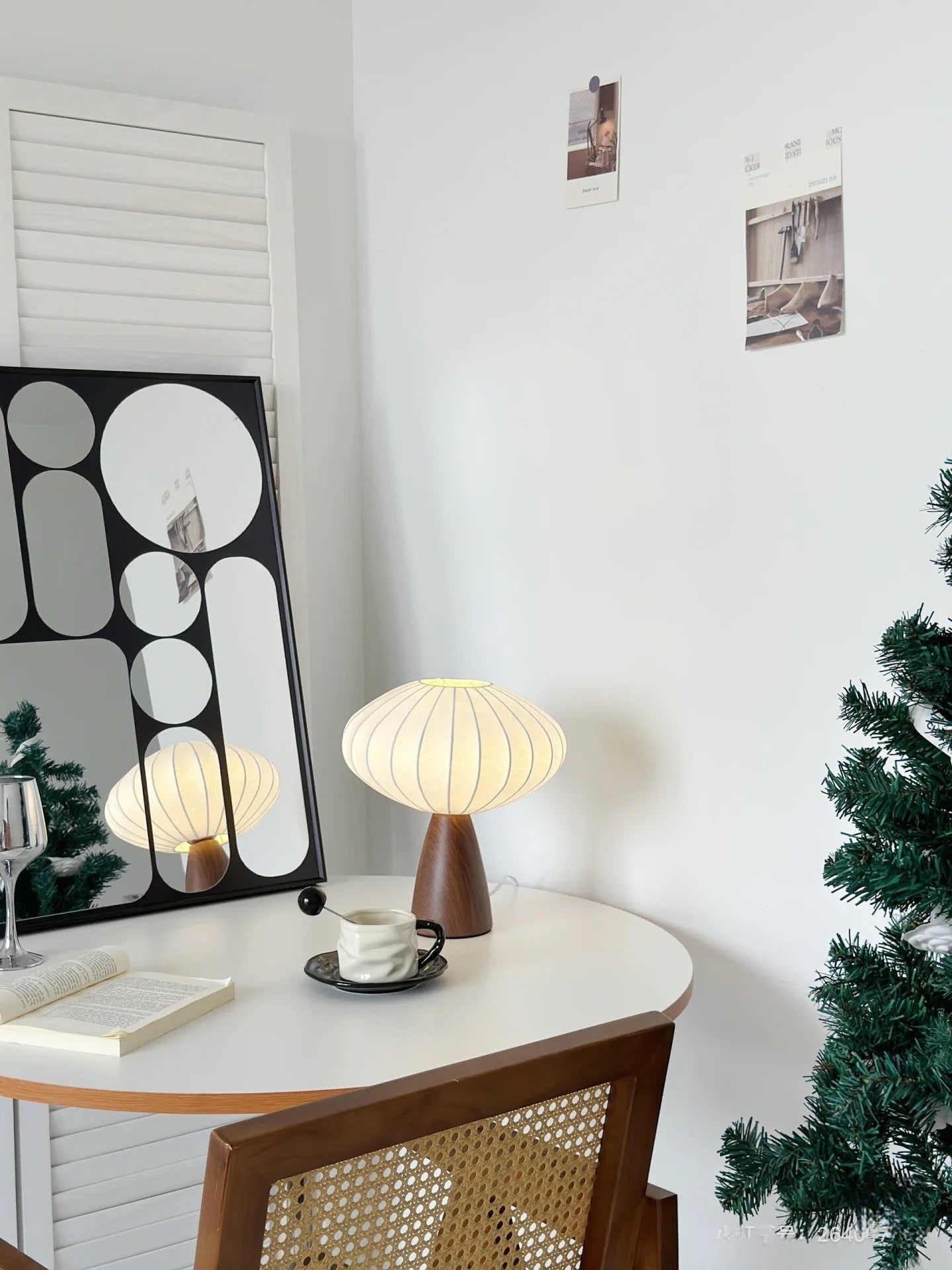 Modern interior with a japandi table lamp, mirror, and decorative items on a white wall.