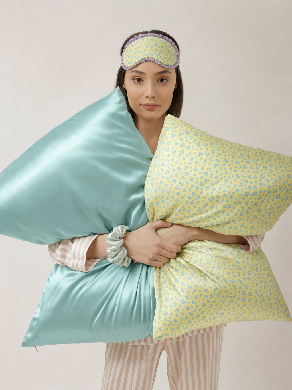 Model holding Tiffany Blue and Yellow Leopard 22 momme silk front pillowcases while wearing a matching sleep mask.