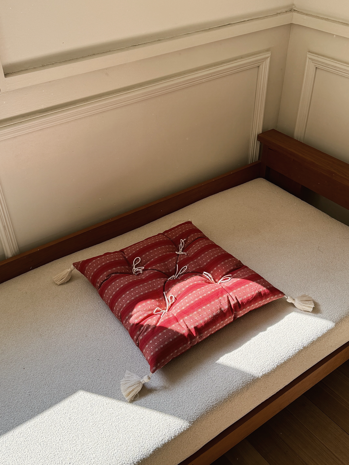 Vintage Red Dot Mariette tufted tassel throw pillow displayed on a sunlit bench.