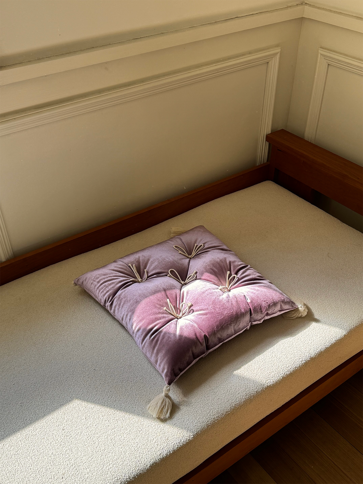 Purple Velvet Léonie tufted tassel throw pillow displayed on a sunlit bench.
