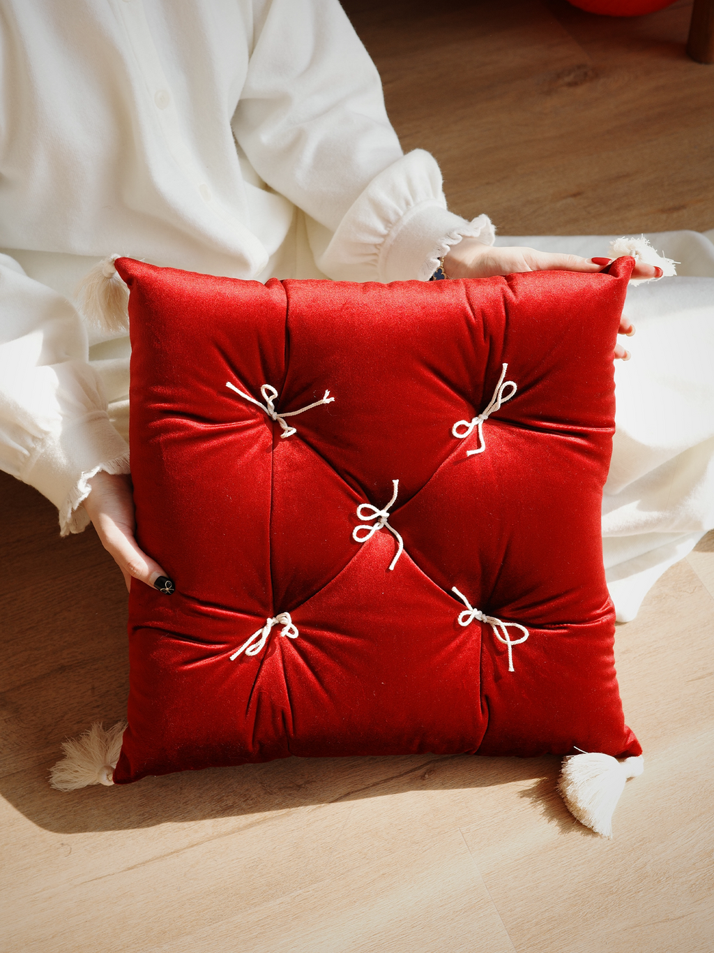 Rouge Velvet Léonie tufted tassel throw pillow held in natural light.